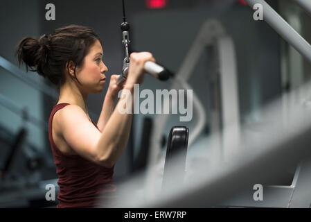 Razza mista donna utilizzando macchina ginnica in palestra Foto Stock