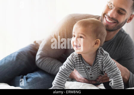 Padre sorridente giocando con il bambino figlio sul letto Foto Stock