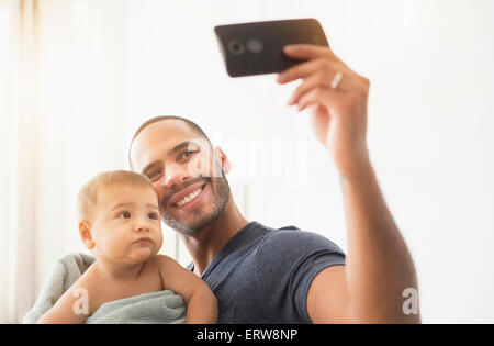 Padre tenendo cellulare fotografia con baby figlio Foto Stock