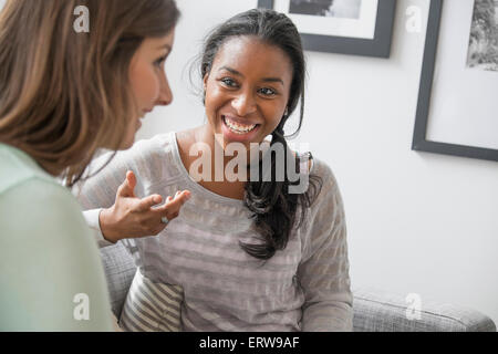 Donna sorridente parlando sul divano Foto Stock