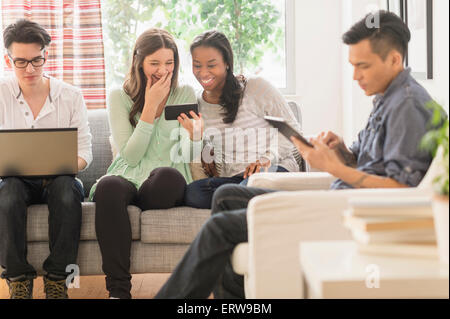 Gli amici utilizzando la tecnologia in salotto Foto Stock