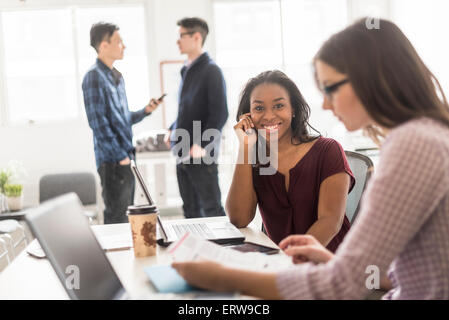 Imprenditrice sorridente con la tecnologia in ufficio Foto Stock