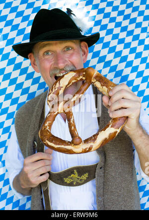 Ritratto di un uomo bavarese di mangiare un pretzel gigante Foto Stock