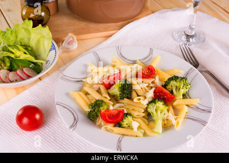 Pasta penne con broccoli, pomodori e mozzarella servita su una piastra Foto Stock