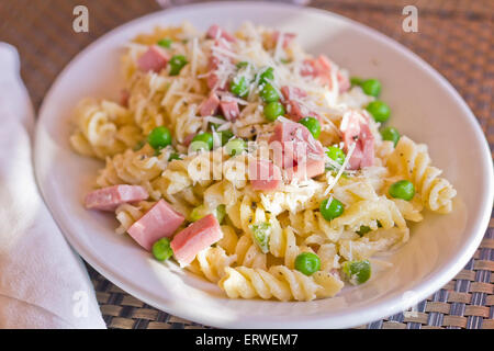 Insalata di pasta con prosciutto e piselli verdi e rabboccato con parmigiano grattugiato Foto Stock