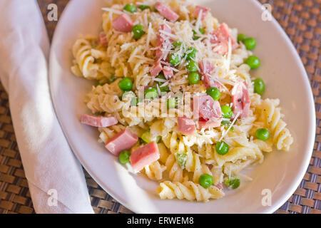 Insalata di pasta con prosciutto e piselli verdi e rabboccato con parmigiano grattugiato Foto Stock