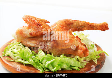 Croccanti di pelle di pollo arrosto con lattuga trinciato sul bordo di taglio Foto Stock