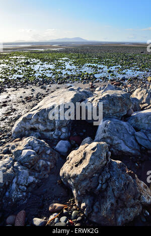 Guardando fuori attraverso il solway dalla spiaggia allonby West Cumbria con rocce di grandi dimensioni in primo piano Foto Stock