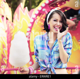 Sorriso Toothy. Giovane donna con cotone Candy nel parco di divertimenti Foto Stock