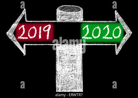 Frecce opposte con l'anno 2019 rispetto al 2020. Disegno a mano con un gessetto sulla lavagna. Scelta immagine concettuale Foto Stock