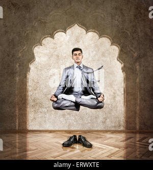 Commerciante indiano di fare meditazione in aria in lotus pongono in ufficio con arco sulla parete Foto Stock