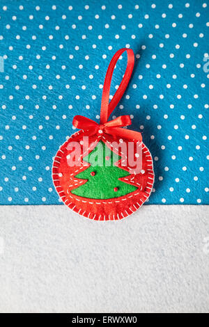 Giocattolo artigianale con albero di Natale dal feltro su sfondo blu con i fiocchi di neve Foto Stock