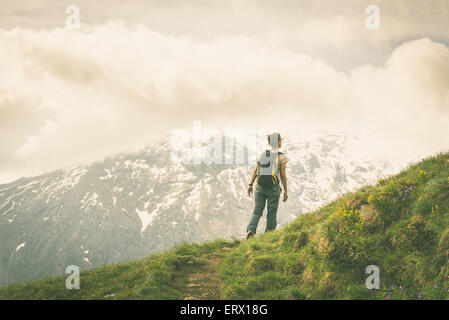 Escursionista femmina con zaino camminando sul sentiero panoramico delle Alpi. Concetto di raggiungere il traguardo e conquistando la vetta. Foto Stock