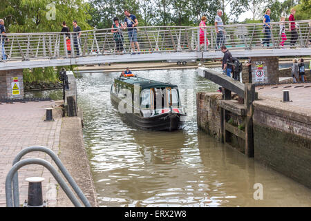 Un canale di manovra in barca attraverso i cancelli di blocco con persone che guardano dal ponte al di sopra di Foto Stock