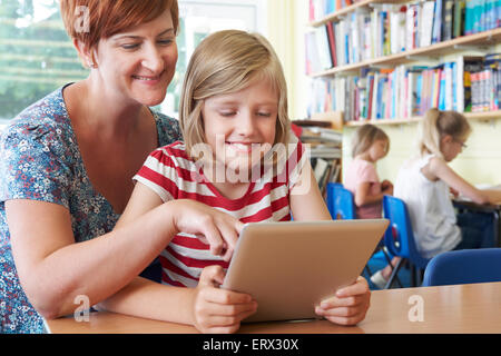 Scolaro con insegnante con tavoletta digitale computer in classe Foto Stock