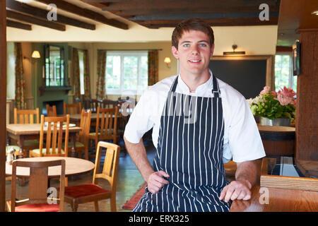 Lo Chef indossando i bianchi e grembiule seduti nel ristorante Foto Stock