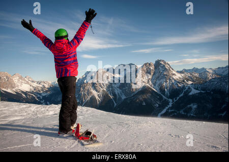 Snowboarder femmina alzando le braccia Foto Stock