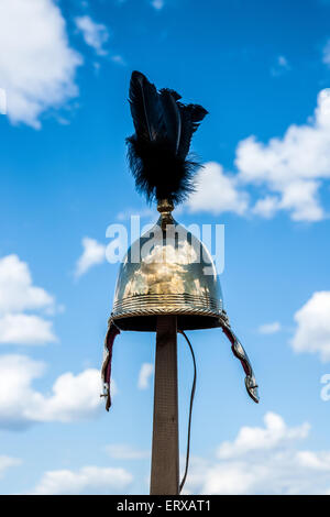 Militare romano il casco con piume nere sulla parte superiore si blocca su un palo di legno contro lo sfondo del cielo blu e nuvole bianche Foto Stock