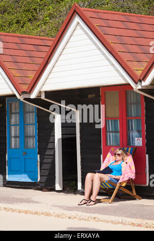 Bournemouth Dorset, Regno Unito. Il 9 giugno, 2015. Donna seduta in sedia a sdraio fuori beach hut lettura a Bournemouth Beach. Credito: Carolyn Jenkins/Alamy Live News Foto Stock