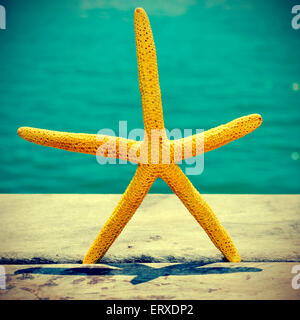 Primo piano di una stella gialla su un vecchio molo in legno sul mare, con un effetto retrò Foto Stock