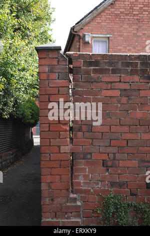 Un muro di mattoni cadere da un altro muro di mattoni per il quale essa era stata attaccata Foto Stock