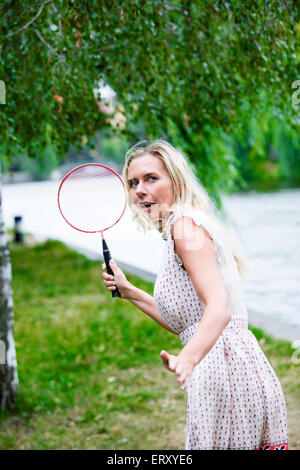 Donna bionda la riproduzione di badminton in un parco Foto Stock