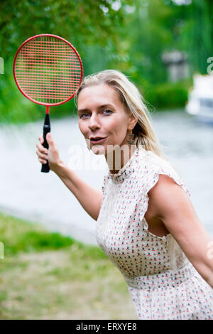 Donna bionda la riproduzione di badminton in un parco Foto Stock