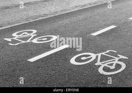 Bicicletta segno su strada a doppia corsia su asfalto bagnato Foto Stock