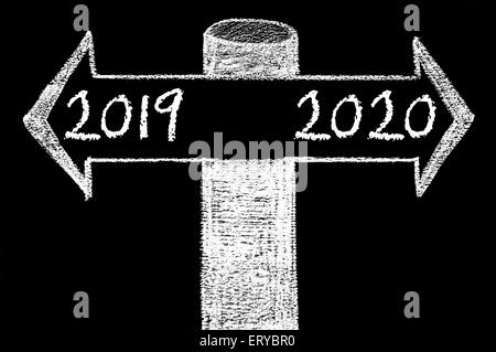 Frecce opposte con l'anno 2019 rispetto al 2020. Disegno a mano con un gessetto sulla lavagna. Scelta immagine concettuale Foto Stock