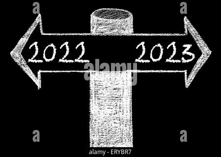 Frecce opposte con l'anno 2022 rispetto all anno 2023. Disegno a mano con un gessetto sulla lavagna. Scelta immagine concettuale Foto Stock