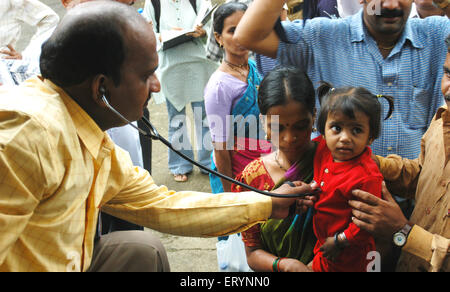 Un medico esamina un bambino in campo medico per il 26 luglio 2005 colpite dalle alluvioni residenti ; i timori di epidemie ; Bombay Mumbai Foto Stock