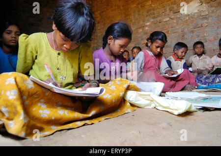 Bambini tribali ragazze e ragazzi che imparano a scuola gestito da ONG Organizzazione non governativa nel villaggio seduto al piano India Asia Foto Stock