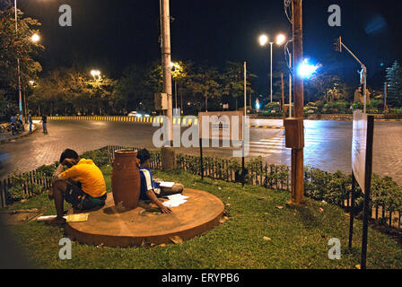 Studenti che studiano sotto luci di strada in Roundabout , Bombay , Mumbai , Maharashtra , India , Asia Foto Stock