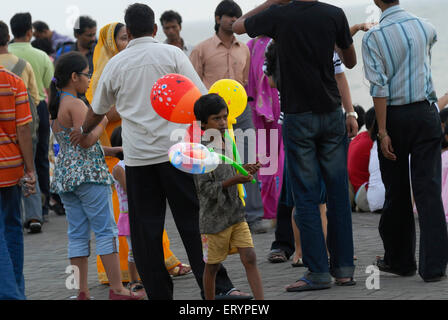 Giovane ragazzo vende palloncini colorati per i turisti in visita a Marine Drive in Mumbai Bombay ; Maharashtra ; India Foto Stock