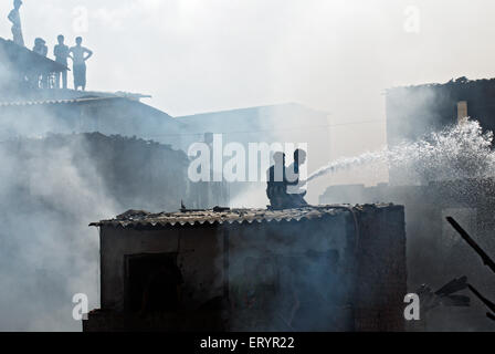 Abitatori spegnimento incendio in baraccopoli Behrampada ; Bandra ; Mumbai Bombay ; Maharashtra ; India 18 Giugno 2009 Foto Stock