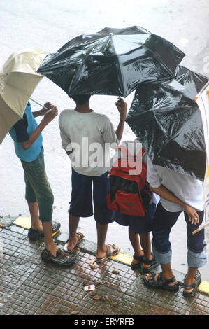 Bambini in piedi con ombrelli in pioggia , Bombay , Mumbai , Maharashtra , India , monsone indiano , Asia Foto Stock