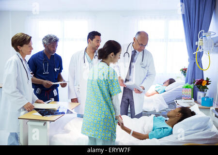 Medici e infermieri facendo turni nella stanza di ospedale Foto Stock