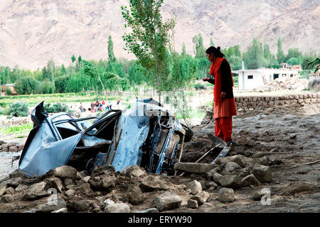 Donna che guarda auto danneggiata a causa di alluvione rapida in saboo ; Leh ; Ladakh ; Jammu e Kashmir ; India NOMR Foto Stock