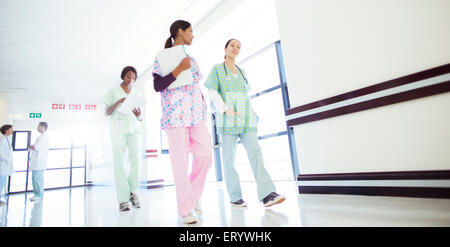 Gli infermieri a parlare e a camminare nel corridoio di ospedale Foto Stock