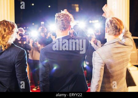 Celebrità gesticolando e fotografata da paparazzi fotografi al red carpet event Foto Stock