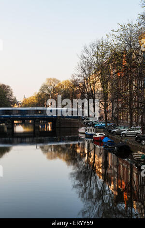 Canale di Amsterdam con il tram attraversando un ponte Foto Stock