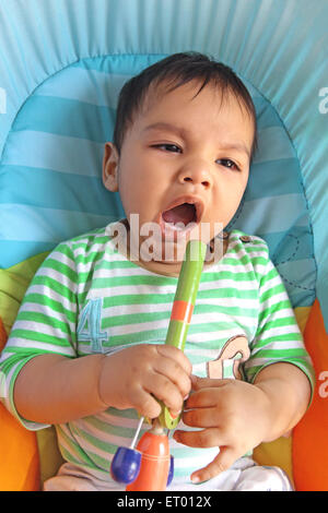 Baby boy sbadigli stanchi con il giocattolo di legno in mano signor#732 Foto Stock