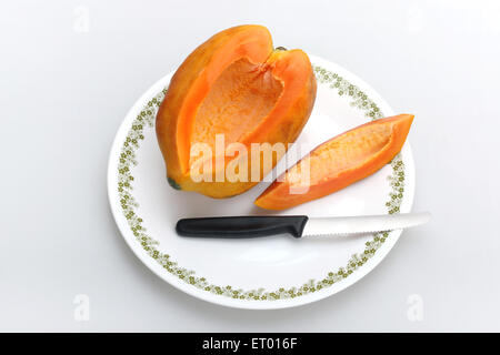 Frutti ; Latino papaia Carica papaya slice e coltello su una piastra bianca Foto Stock