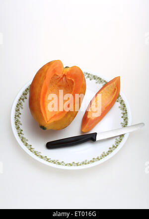 Frutti ; Latino papaia Carica papaya slice e coltello su una piastra bianca Foto Stock