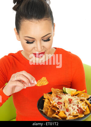 Giovane donna ispanica con un piatto di stile Messicano Nachos ricoperti in malto grattugiate il formaggio e una salsa piccante salsa isolata contro uno sfondo bianco Foto Stock