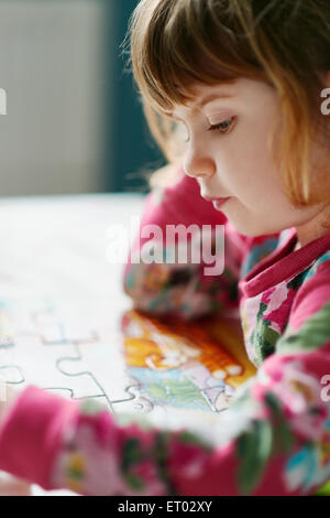 Close up di grave ragazza assemblaggio di puzzle Foto Stock