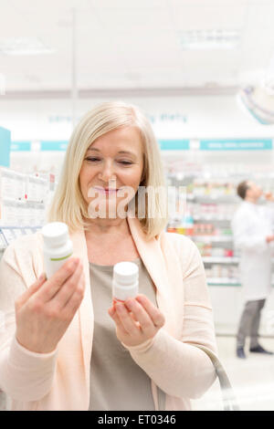 Il cliente la lettura di etichette su bottiglie in farmacia Foto Stock