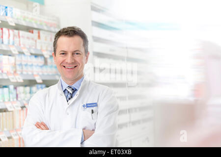 Ritratto di farmacista sorridente con le braccia incrociate in farmacia Foto Stock
