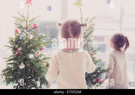 Ragazze decorare piccoli alberi di Natale Foto Stock