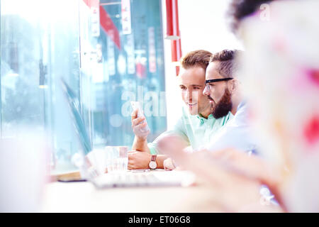 Imprenditori texting con un telefono cellulare in cafe Foto Stock